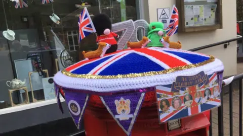 Ray Donelan A knitted post box topper showing beefeaters, the queen and a union jack in Groombridge, Kent