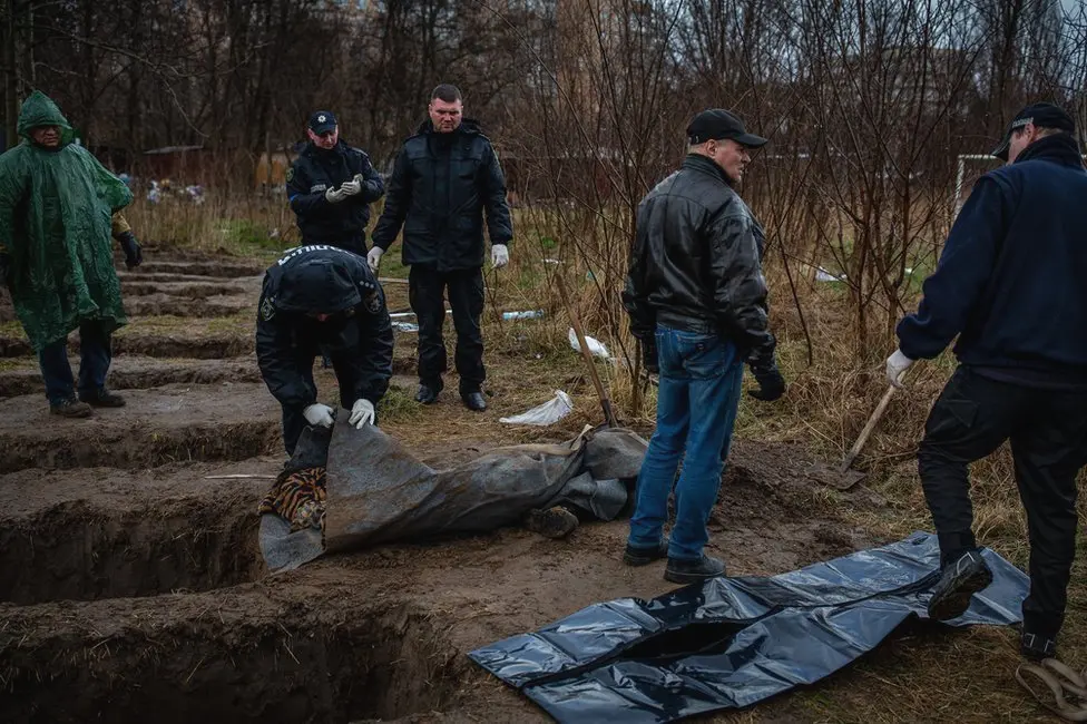 BBC Nine graves, dug by neighbours behind apartment buildings in Bucha.