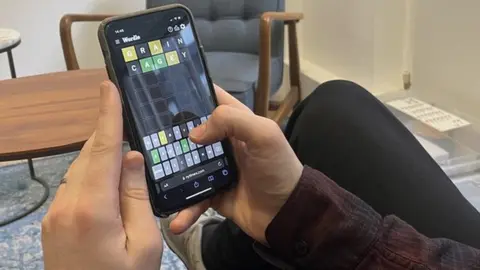 Tom Young plays Wordle on a mobile phone