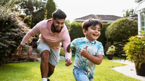 Getty Images Man plays chase with a young boy in a garden