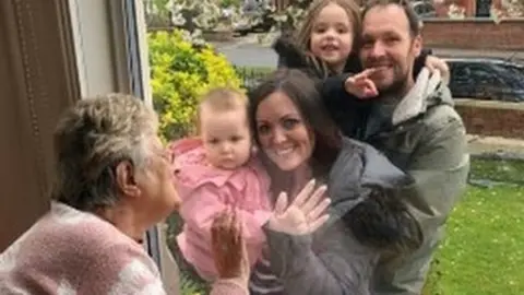 Anchor House A resident saying hello to family members through the window