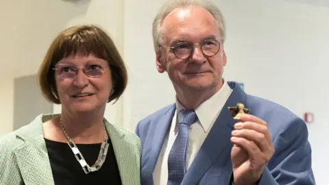 Reuters Saxony-Anhalt State Premier Reiner Haseloff of the Christian Democratic party (CDU), and his wife Gabriele, wait for the first election polls to be published for the federal state election of Saxony-Anhalt, in Magdeburg, Germany, June 6, 2021