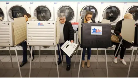 Reuters Several people are shown standing in voting booths in a Laundromat