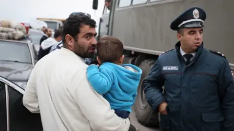 AFP via Getty Images A man and his son crossing the border at a registration centre of the Armenian foreign affairs ministry, near the border town of Kornidzor