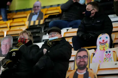 Reuters Football fans sit in the stands next to cardboard cut-outs