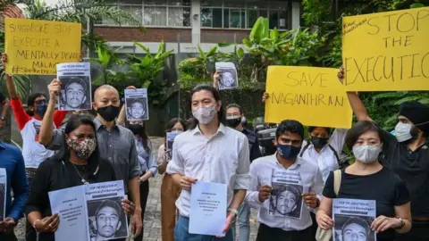 Getty Images Activists hold placards before submitting a memorandum to parliament in protest at the impending execution of Nagaenthran K. Dharmalingam