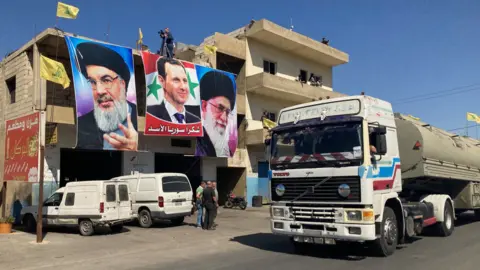 BBC Posters of Hezbollah leader Hassan Nasrallah, Syrian President Bashar al-Assad and Iranian Supreme Leader Ali Khamenei on a building in al-Ain, as lorries bring Iranian fuel from Syria into Lebanon (16 September 2021)