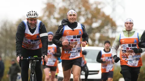 PA Media Kevin Sinfield running with his support team
