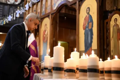 DANIEL LEAL/AFP Mayor of London Sadiq Khan lights a candle, part of the 52 candles symbolising the 52 weeks of the conflict, during the ecumenical prayer service at Ukrainian Catholic Cathedral, in London, 24 February 2023