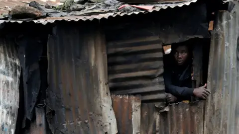 Reuters A man watches as protesters clash with riot police attempting to disperse supporters of Kenyan opposition leader Raila Odinga in Kibera slums of Nairobi. 26/10/2017