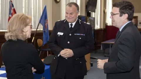 PA Media Stephen Watson (centre) alongside Beverley Hughes, Deputy Mayor for Policing, Crime, Criminal Justice and Fire, and Mayor of Greater Manchester Andy Burnham, as he is sworn i