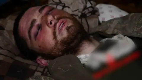 Image of Hlib Stryzhko lying injured with eyes closed