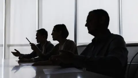Getty Images Silhouette of business people negotiating at meeting table