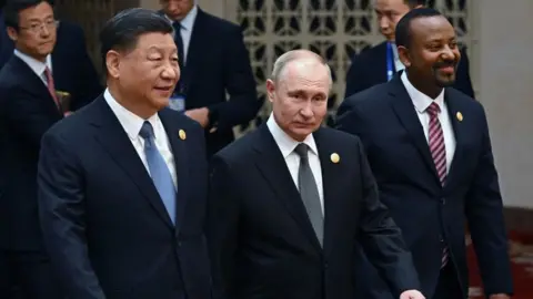 Getty Images This pool photograph distributed by Russian state owned agency Sputnik shows Russia's President Vladimir Putin and Chinese President Xi Jinping heading to a group photo session during the third Belt and Road Forum for International Cooperation at the Great Hall of the People in Beijing on October 18, 2023.