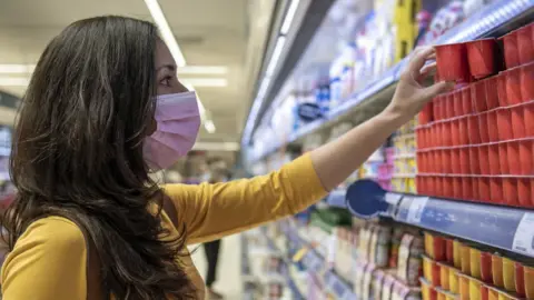 Getty Images Young woman choosing yogurts at the supermarket. - stock photo