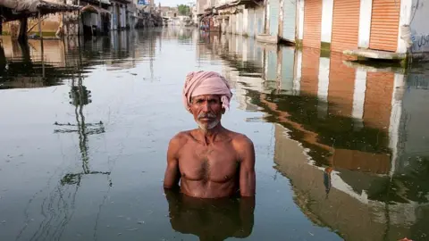 A man wearing a turban stands in the centre of Khairpur Nathan Shah town in Pakistan, which has been totally submerged by floodwaters.