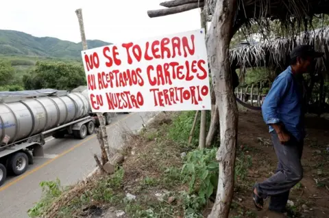 Reuters A sign reads: "We do not tolerate nor accept drug cartels in our territory" at a checkpoint in Mexico