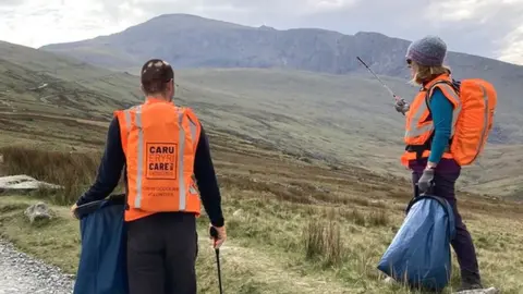 Litter pickers on a path with rubbish bags