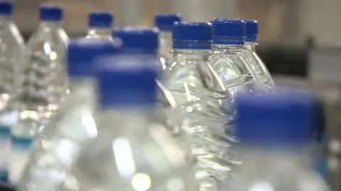 BBC Plastic bottles on factory conveyer