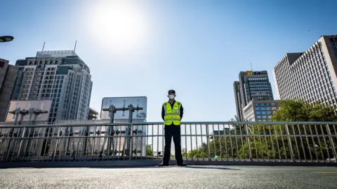 BBC/ED LAWRENCE A police officer stands guard at a bridge in Beijing