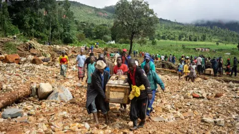 Getty Images Wooden graves are carried along a makeshift path