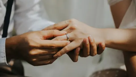 Getty Images Couple's hands exchanging ring