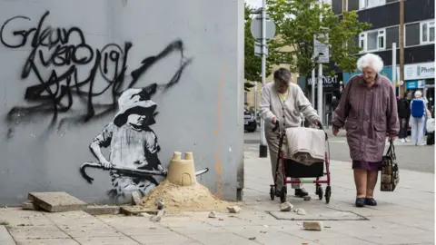 Banksy / PA Media The artwork in situ on a former shop wall in Lowestoft in August 2021