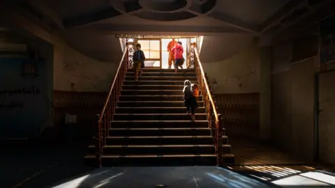 Girl climbs the stairs of her school in a basement in Kabul after lessons