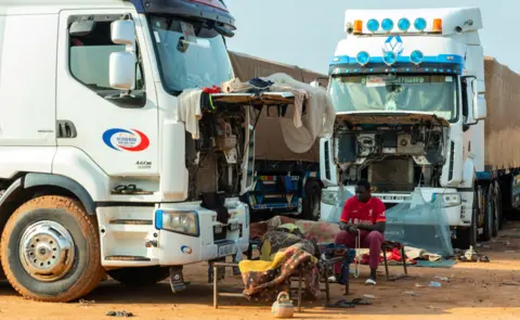 Didier Assogba/EPA Drivers rest next to parked lorries near the border town of Malanville, Benin - Wednesday 16 August 2023