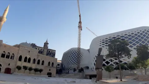 AFP The façade a new Beirut commercial complex designed by the late British-Iraqi architect Zaha Hadid. On the left is the Lebanese capital's Majidiyah mosque. 5 August 2020