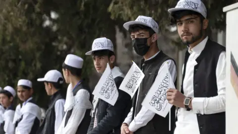 AFP Afghan school boys holding Taliban flags align during a ceremony held to mark the start of the new academic year at Amani High School in Kabul on March 20, 2024.