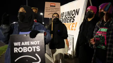 Reuters People hold up signs during a rally outside the Amazon warehouse, in Coventry, Britain, on 25 January 2023