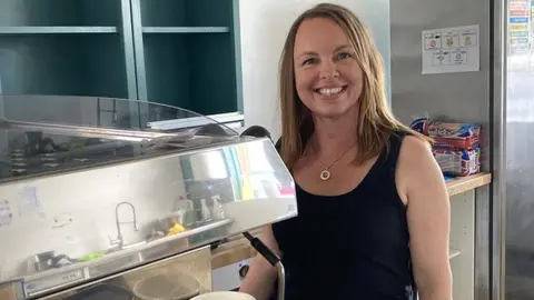 A woman standing by a coffee machine