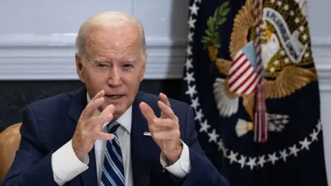 Getty Images Joe Biden sitting with hands raised, before flag