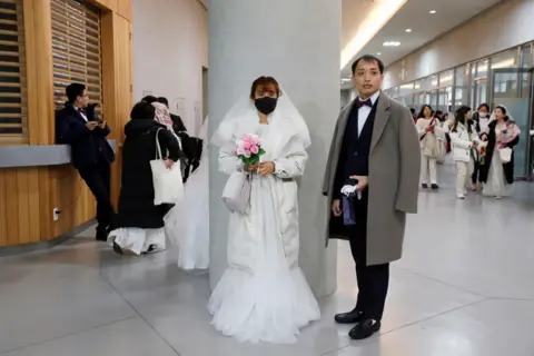 Reuters A bride wearing a mask for protection from the new coronavirus, attends a mass wedding ceremony of the Unification Church at Cheongshim Peace World Centre in Gapyeong,