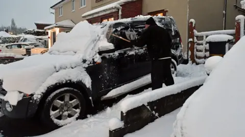 PA A motorist clears the snow from a 4x4 vehicle in Bristol