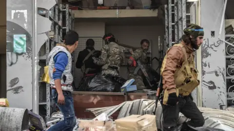 AFP Turkish-backed Syrian rebel fighters loot a shop in the Syrian city of Afrin (18 March 2018)