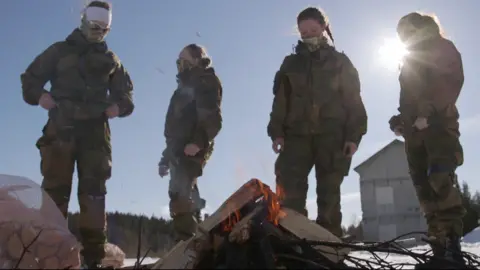 Mohamed Madi/BBC Soldiers stand around a fire