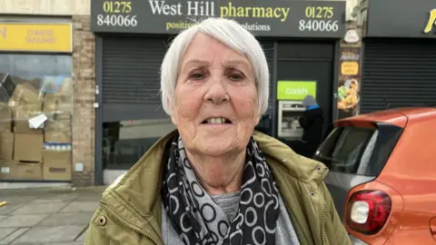 BBC Joy Knight standing in front of the West Hill Pharmacy in Portishead