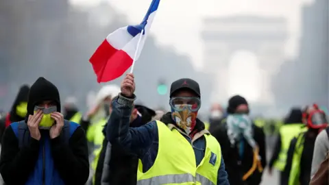 Reuters Masked protesters wearing yellow vests, a symbol of a French drivers" protest against higher fuel prices, take part in a demonstration on the Champs-Elysees in Paris, France, November 24, 2018.