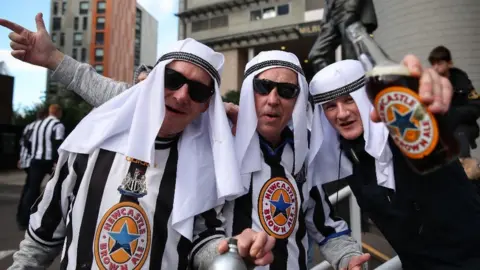 Getty Images Newcastle fans with Newcastle Brown Ale after Saudi-led consortium take over