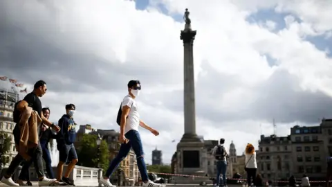 Reuters People wearing protective face masks walks through Trafalgar Square, amid the coronavirus (COVID-19) outbreak, in London