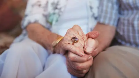 Getty Images Elderly couple holding hands
