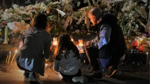 BBC A man lays a tribute to the victims of a mass shooting at a school in Belgrade