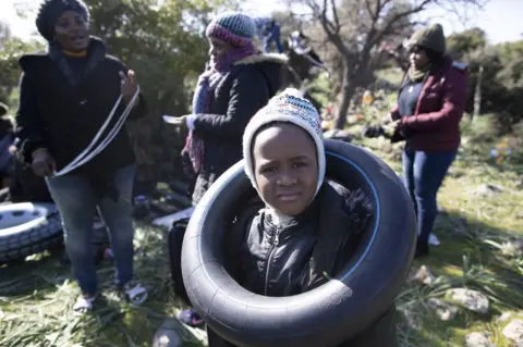 EPA An African migrant boy plays with a rubber ring as they wait before attempting to cross the Aegean Sea by boat to reach the Greek island of Lesbos, in Ayvacik district, Canakkale region, Turkey, 3 March