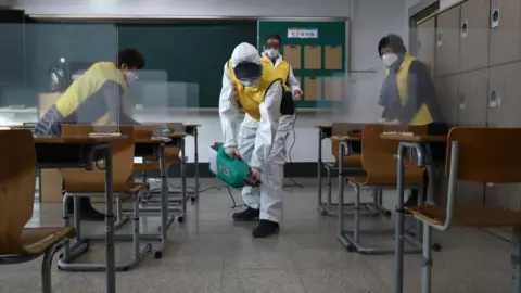 Getty Images Workers disinfect a classroom in Seoul to prevent the spread of the coronavirus ahead of the exams