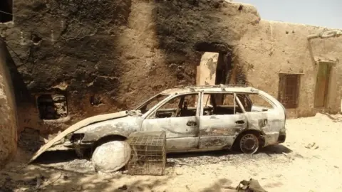 Abdul Aziz Safdari A burned out car next to a badly burned building