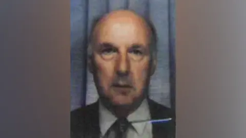 Smith & Co Solicitors Photo of Ronald Gale from his bus pass. Shows an older man wearing a dark suit jacket and tie over a white shirt. He has a partially bald head.