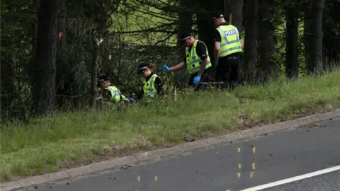 PA Media police searching at the scene of the crash