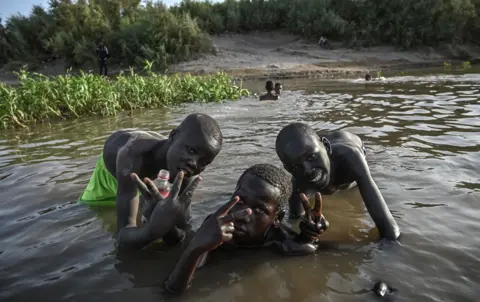 AFP Sudanese boys pose for a picture as they bath in the shallow waters of the Nile River on May 1, 2019 at the Tuti island district of Khartoum